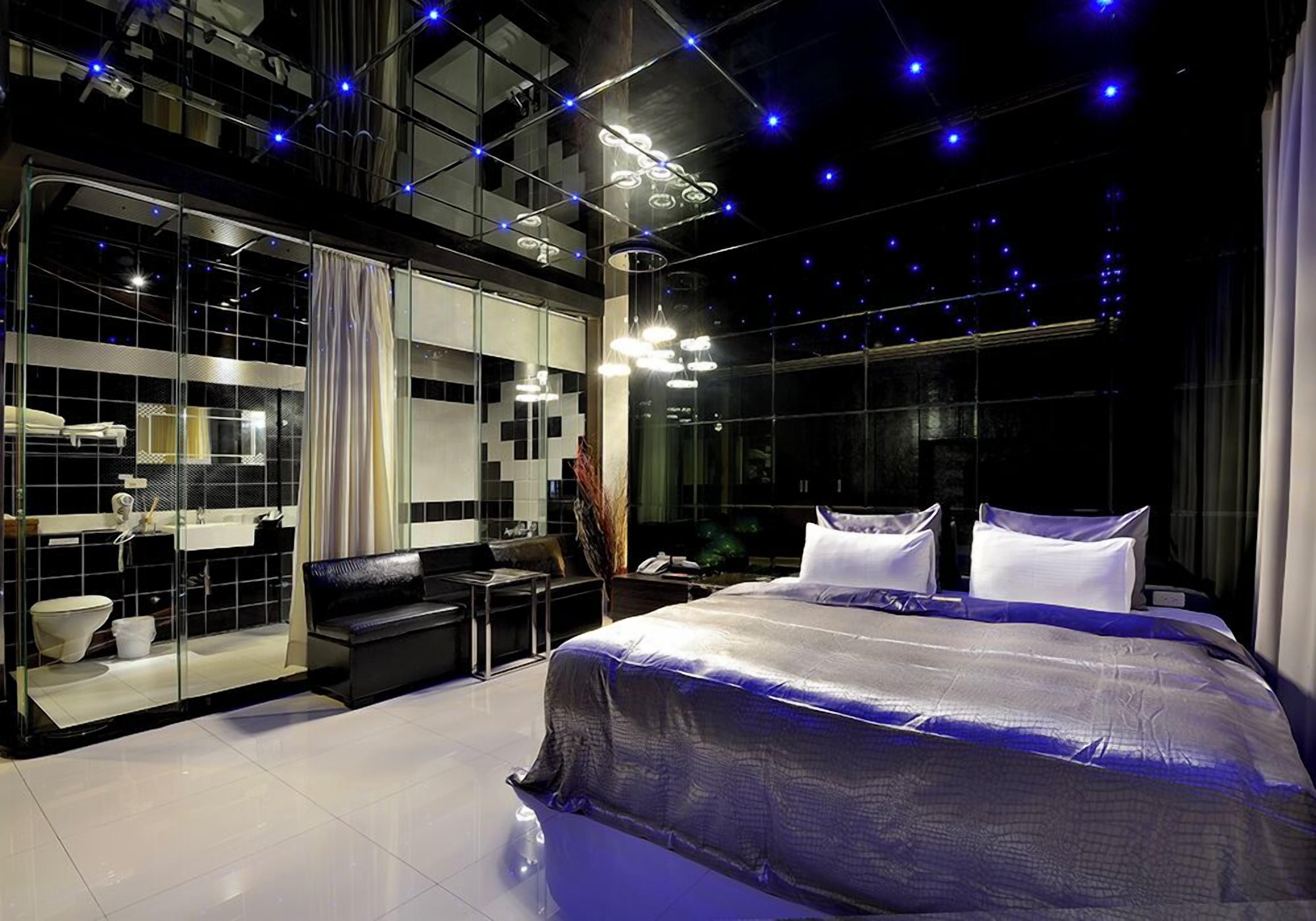 Una habitación de hotel moderna con una cama grande, un baño con mampara de vidrio y vistas a la ciudad.