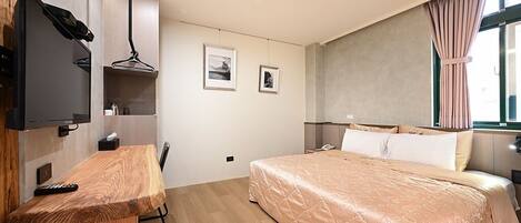Une chambre à coucher avec un lit, un bureau, une télévision et une fenêtre avec des rideaux.