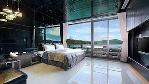 A modern bedroom with a large bed, a TV, and a view of the water. - LakeView Homestay (Yuchi)
