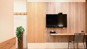 A modern room with a wooden wall, a mounted TV, a wooden desk, a chair, and a plant. - LakeView Homestay (Yuchi)