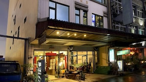 A multi-story hotel with a modern facade, large windows, and a covered entrance area with seating and plants. - LakeView Homestay (Yuchi)