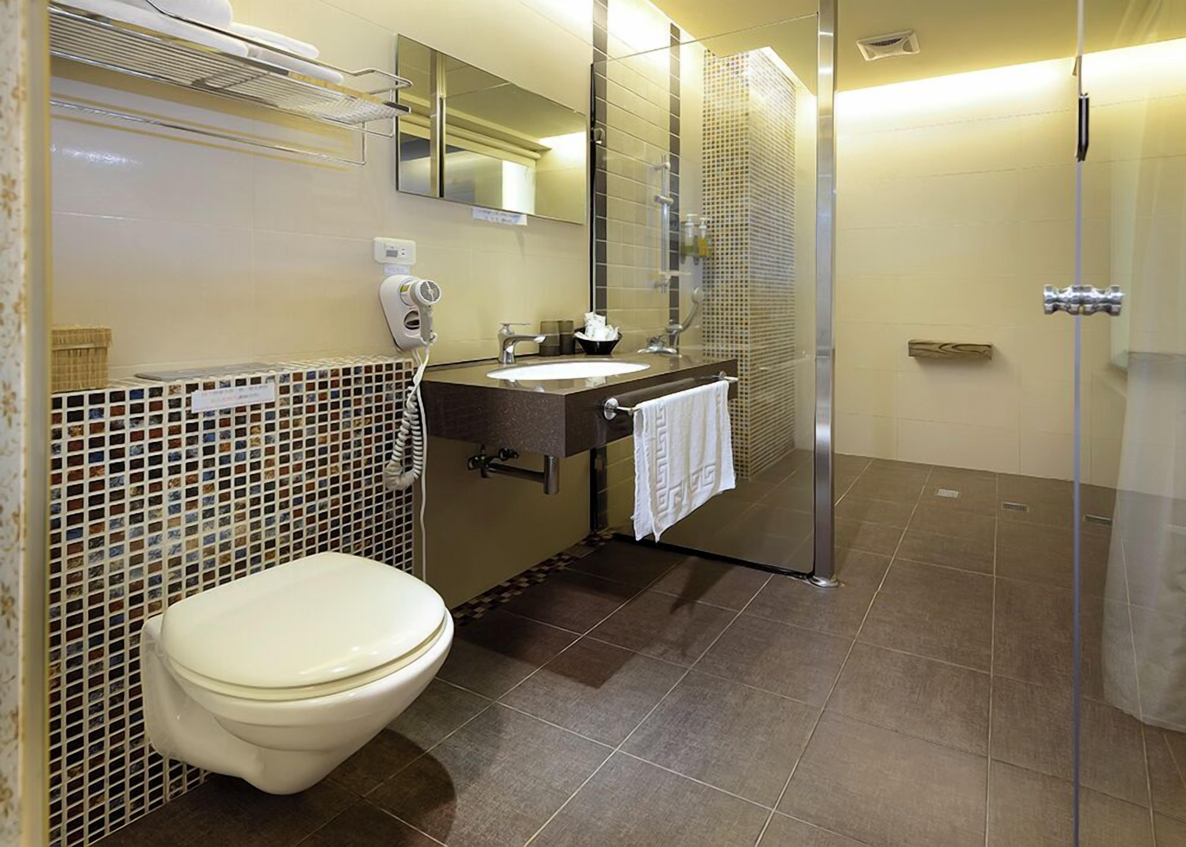 Une salle de bain équipée de toilettes, d’un lavabo, d’un miroir et d’une douche.
