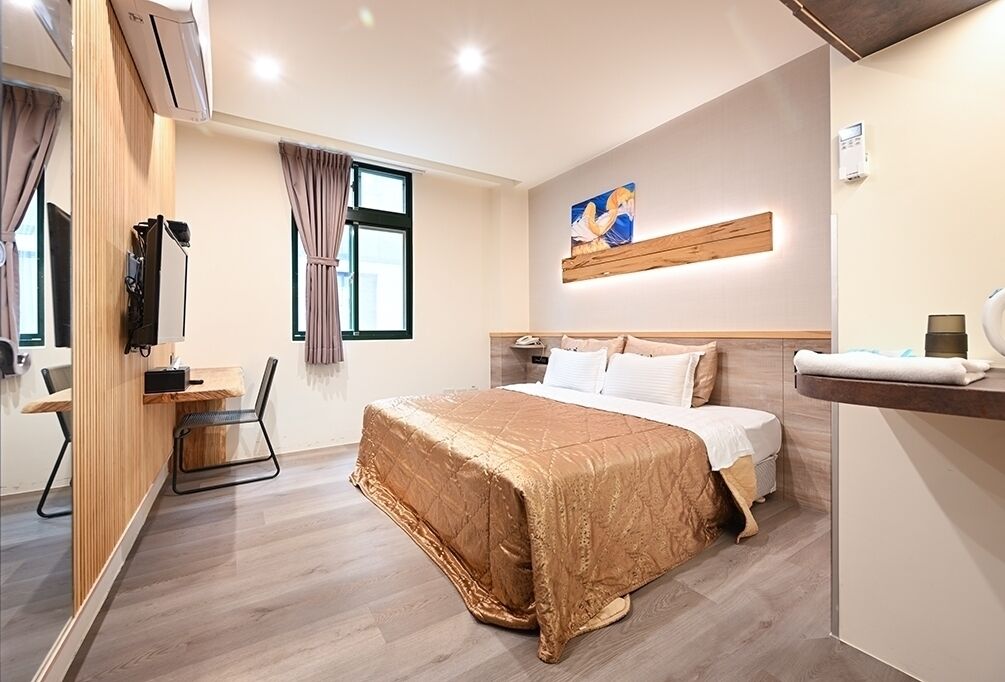 A modern hotel room with a large bed, a desk, and a chair.