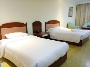 Camera d'albergo con due letti, un comodino con il telefono e una sedia.