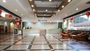 Un área de recepción con suelo a cuadros, mostrador de recepción y mobiliario de mimbre.