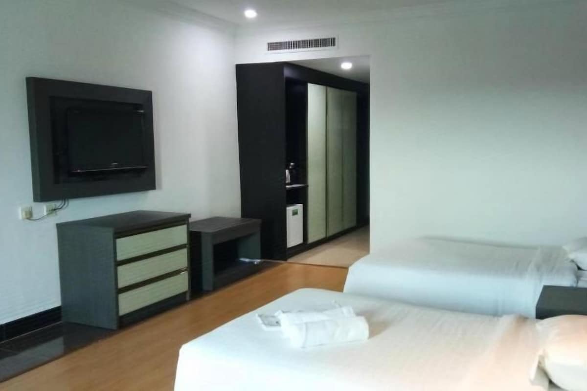 A modern hotel room with a bed, bedside table, TV, and a wardrobe.