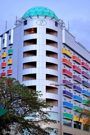 Un hotel a più piani con un caratteristico tetto a cupola e una serie di balconi con ringhiere colorate.