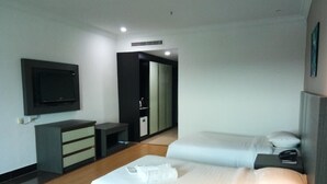 Una habitación de hotel moderna con una cama grande, un televisor montado en la pared, un escritorio y un armario.
