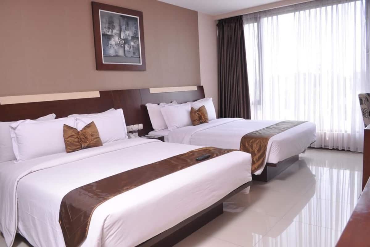 A hotel room with two beds, a nightstand, a framed picture on the wall, and a large window with curtains.