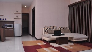Uma sala de estar moderna com um sofá, uma mesa de centro e uma cozinha ao fundo.