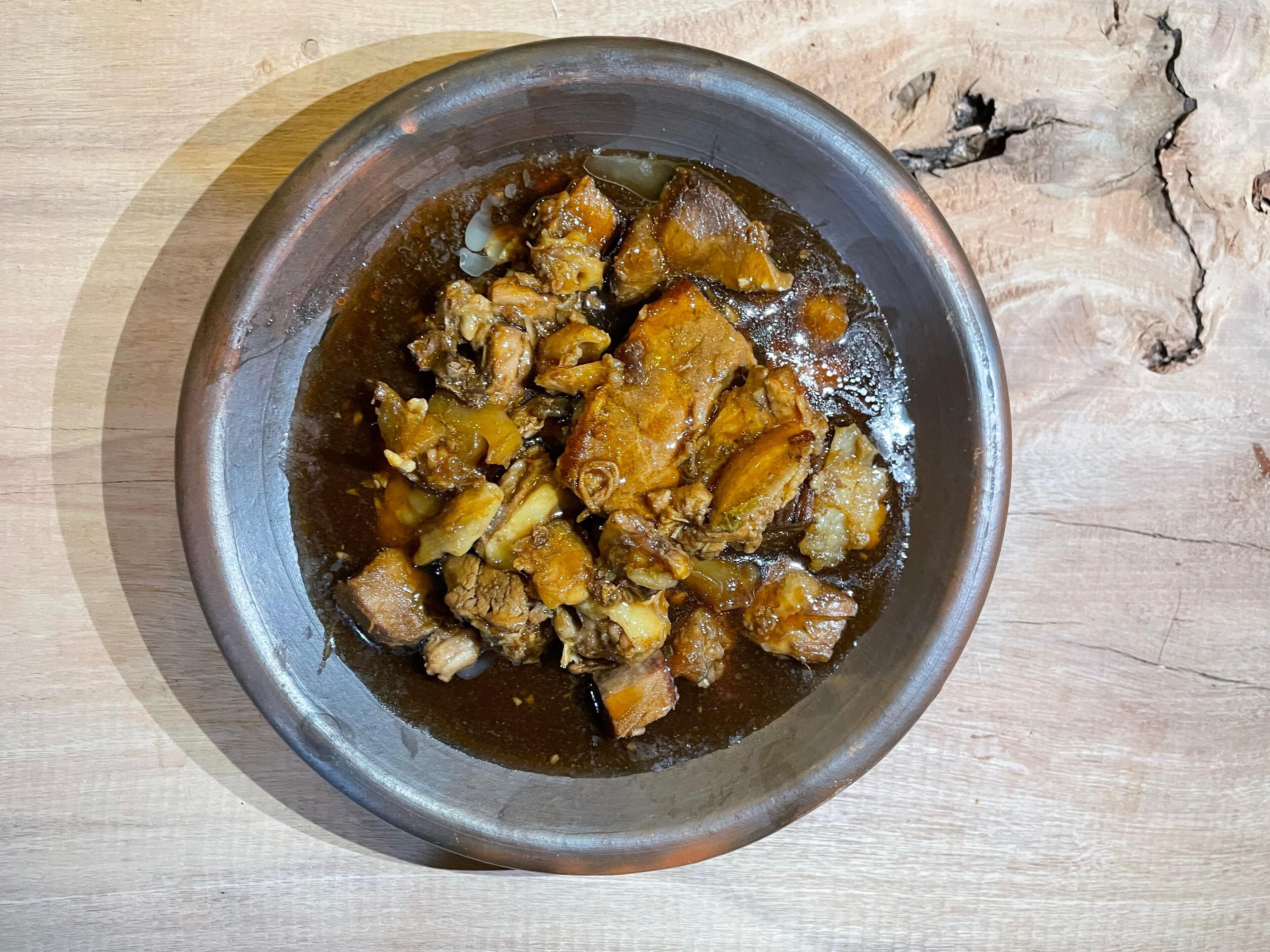 Een schaal eten met een donkere saus, op een houten ondergrond.