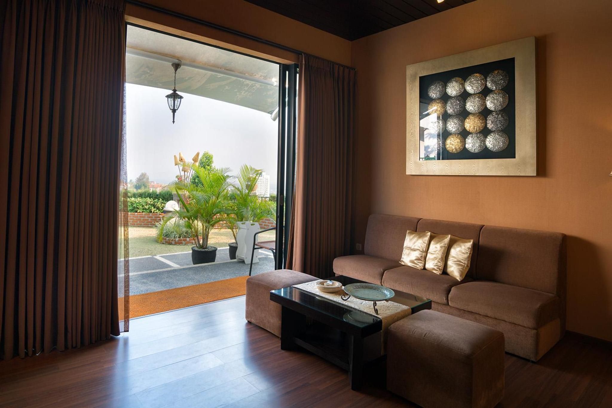 Un salon avec un canapé, une table basse et une vue sur un jardin, visible à travers une porte ouverte.
