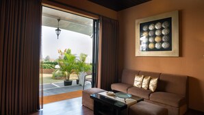 Una sala de estar con un sofá, una mesa de centro y vista a un jardín por una puerta abierta.