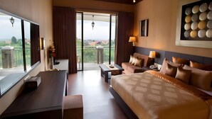 Habitación de hotel con una cama grande, un escritorio, un sofá y un balcón con vistas.