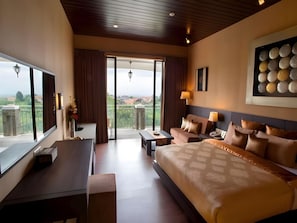 Ein Hotelzimmer mit einem großen Bett, einem Schreibtisch, einem Sofa und einem Balkon mit Blick.