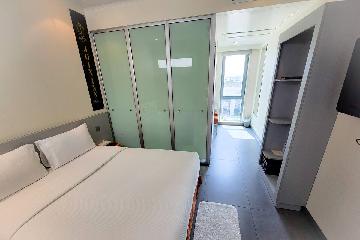 Ein modernes Hotelzimmer mit einem großen Bett, einem Kleiderschrank und einem kleinen Balkon.