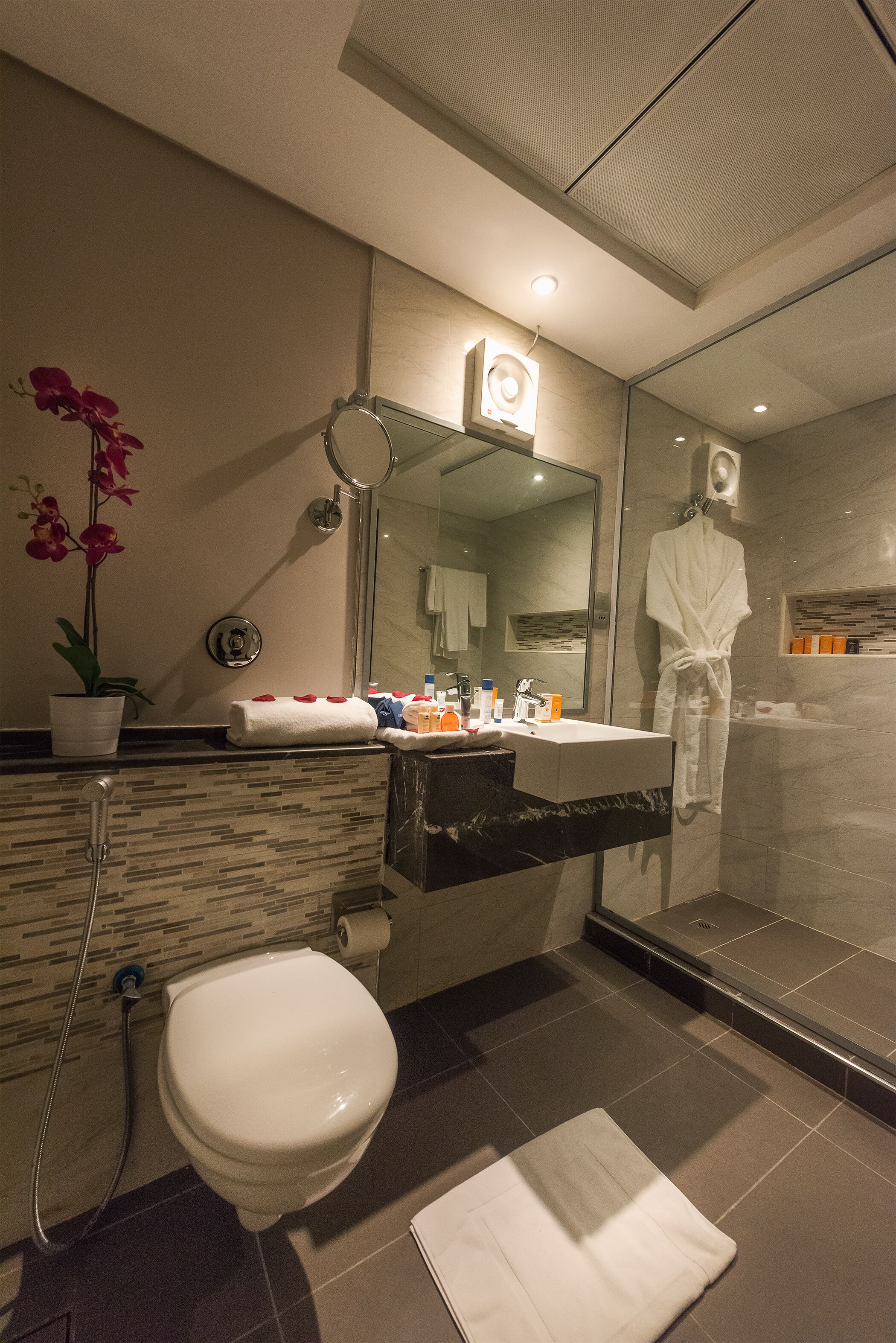 Un baño moderno con inodoro, lavamanos y ducha.