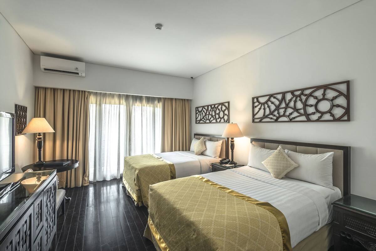 Une chambre d’hôtel avec deux lits, un bureau, une télévision et un appareil de climatisation.