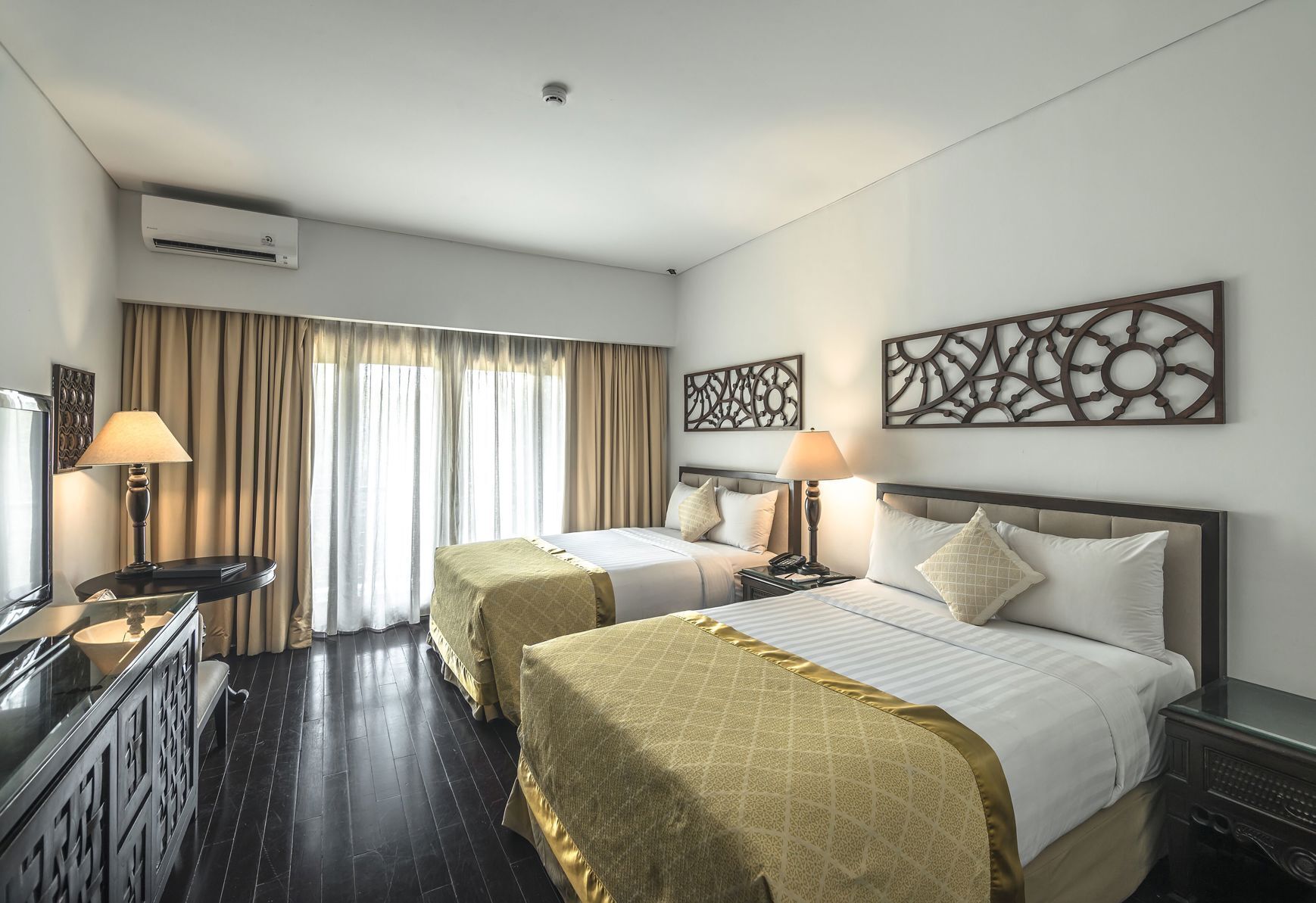Habitación de hotel con dos camas, un escritorio, un televisor y aire acondicionado.
