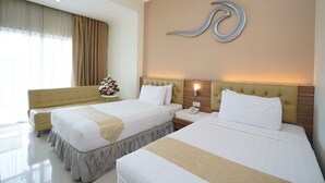 A hotel room with two beds, a sofa, a wall-mounted phone, and a decorative wall piece. - Lorin Sentul Hotel (Bogor)