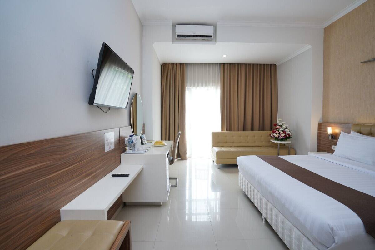 Una habitación de hotel con cama, sofá, escritorio, televisión y baño.