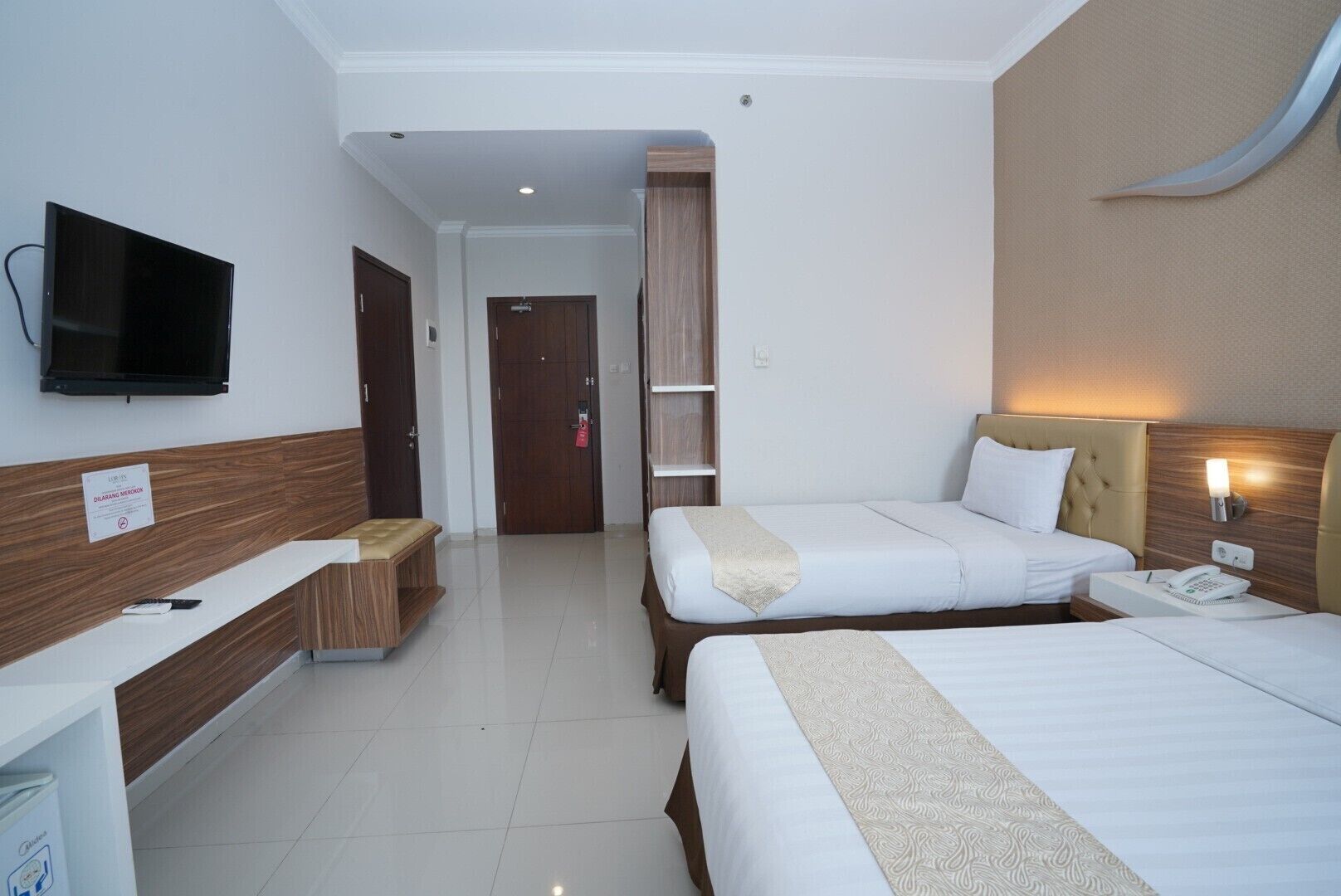 Une chambre d’hôtel avec deux lits, une télévision, un bureau et une porte de salle de bain.