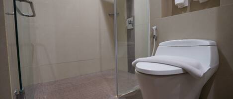 Een moderne badkamer met een douchecabine van glas, een toilet en een handdoekrek met handdoeken.