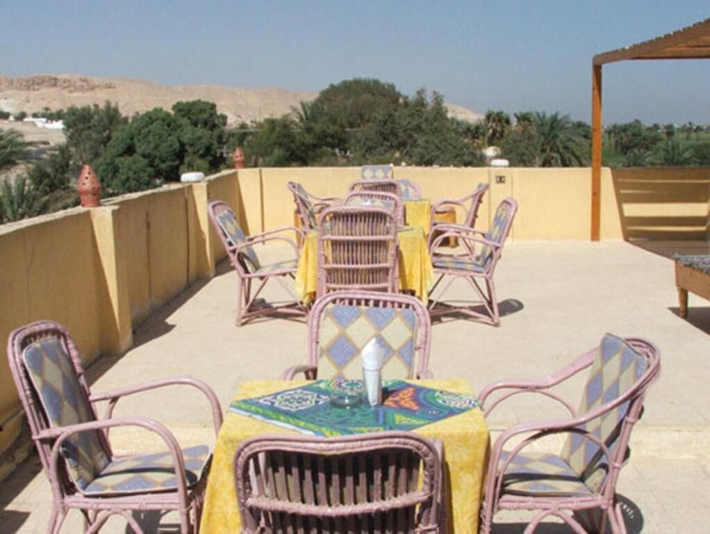 Un patio al aire libre con muebles de mimbre y una mesa cubierta con un mantel estampado.
