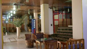 A lobby with wooden furniture, a large potted plant, and a sofa. - Pharaohs Hotel (Luxor)