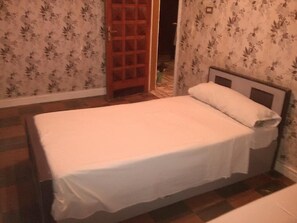 A small, single-bed room with a wooden headboard, floral wallpaper, and a wooden floor. - Pharaohs Hotel (Luxor)