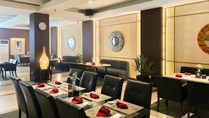 Ein Hotelrestaurant mit gedeckten Tischen für Gäste, gestaltet im modernen Stil mit dunklem Mobiliar und dekorativen Wandspiegeln.