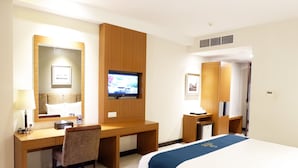 Ein Hotelzimmer mit einem Bett, einem Schreibtisch mit Stuhl, einem Fernseher und einem Spiegel.