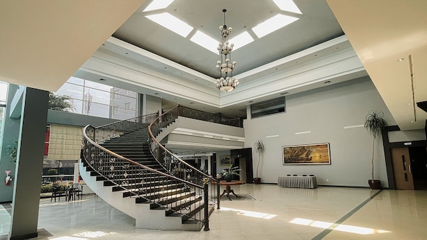 Eine geräumige Lobby mit einer imposanten Treppe, hohen Decken und Oberlichtern.