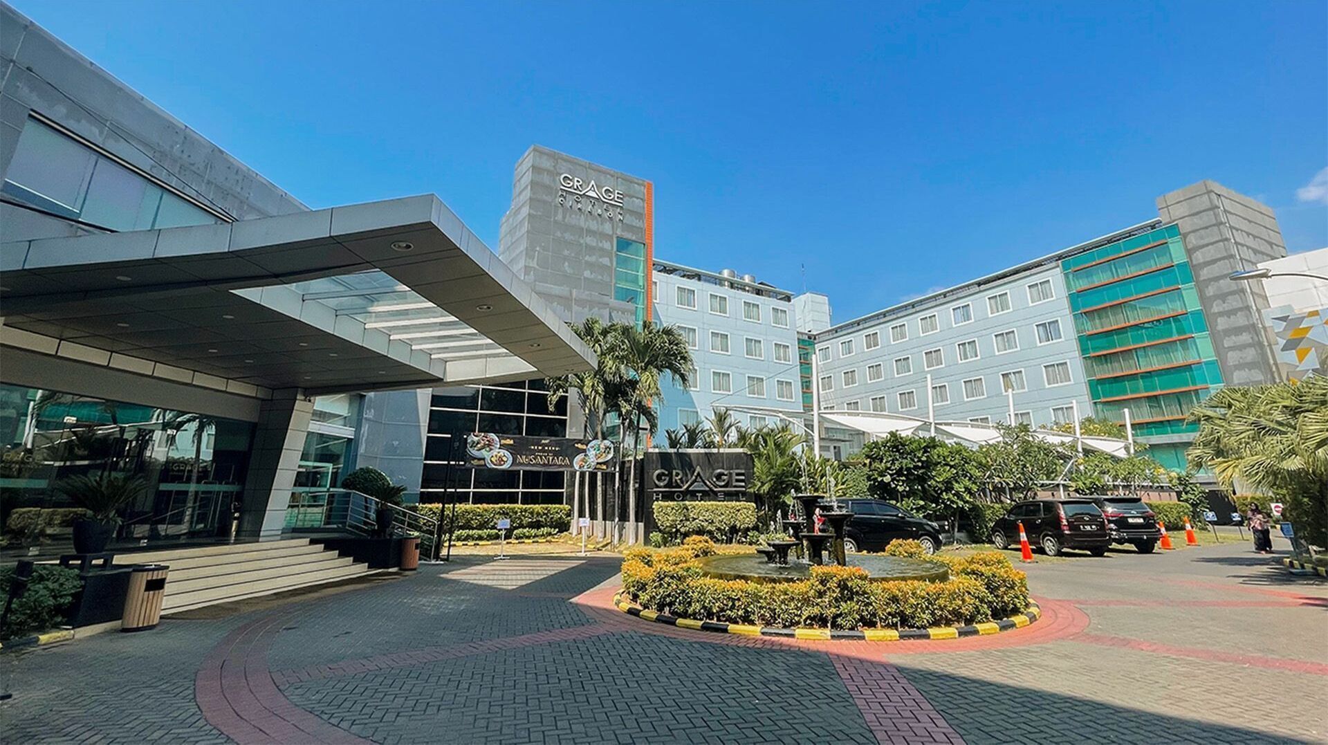 A hotel with a modern facade, a central courtyard with a fountain, and a sign for 'GRAGE HOTEL'.