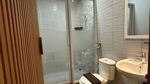 A bathroom with a shower, toilet, and sink. - Satria Cirebon (Cirebon)