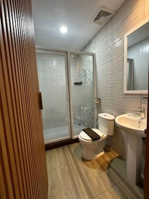 A bathroom with a shower, toilet, and sink. - Satria Cirebon (Cirebon)