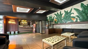 A hotel lobby with a reception desk, seating area, and a mural. - Satria Cirebon (Cirebon)