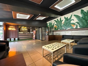 A hotel lobby with a reception desk, seating area, and a mural. - Satria Cirebon (Cirebon)