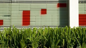 Une façade d’immeuble avec des stores horizontaux et des marquages de sécurité rouges.