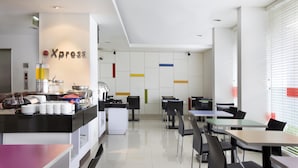 Un café moderne doté d’une machine à café, d’un comptoir de buffet et d’un espace salon avec des tables et des chaises.