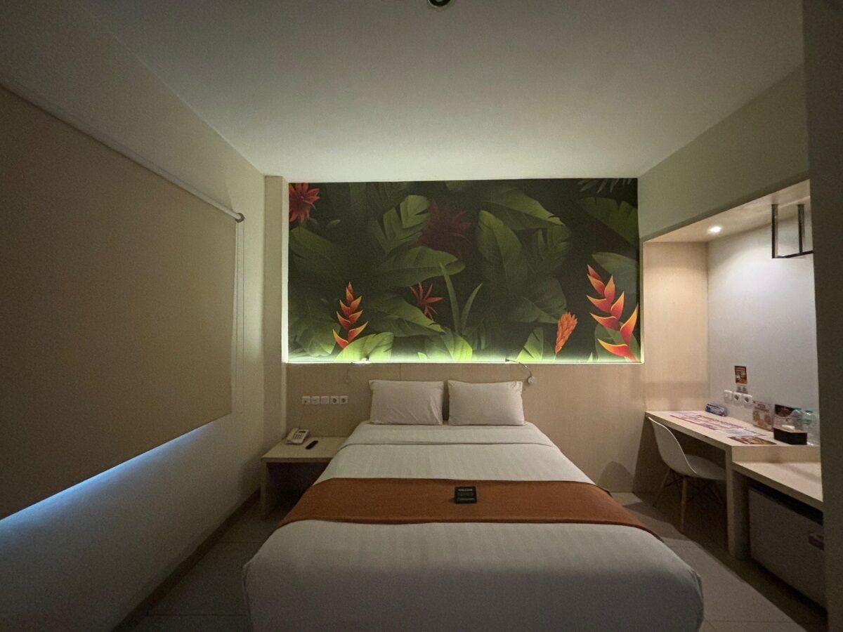 A hotel room with a bed, a desk, and a nightstand.