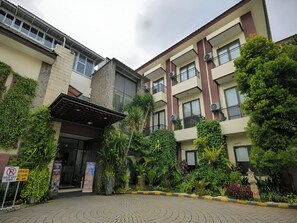 A multi-story building with a covered entrance, balconies, and lush greenery. - D'Bamboo Suites (Jakarta)