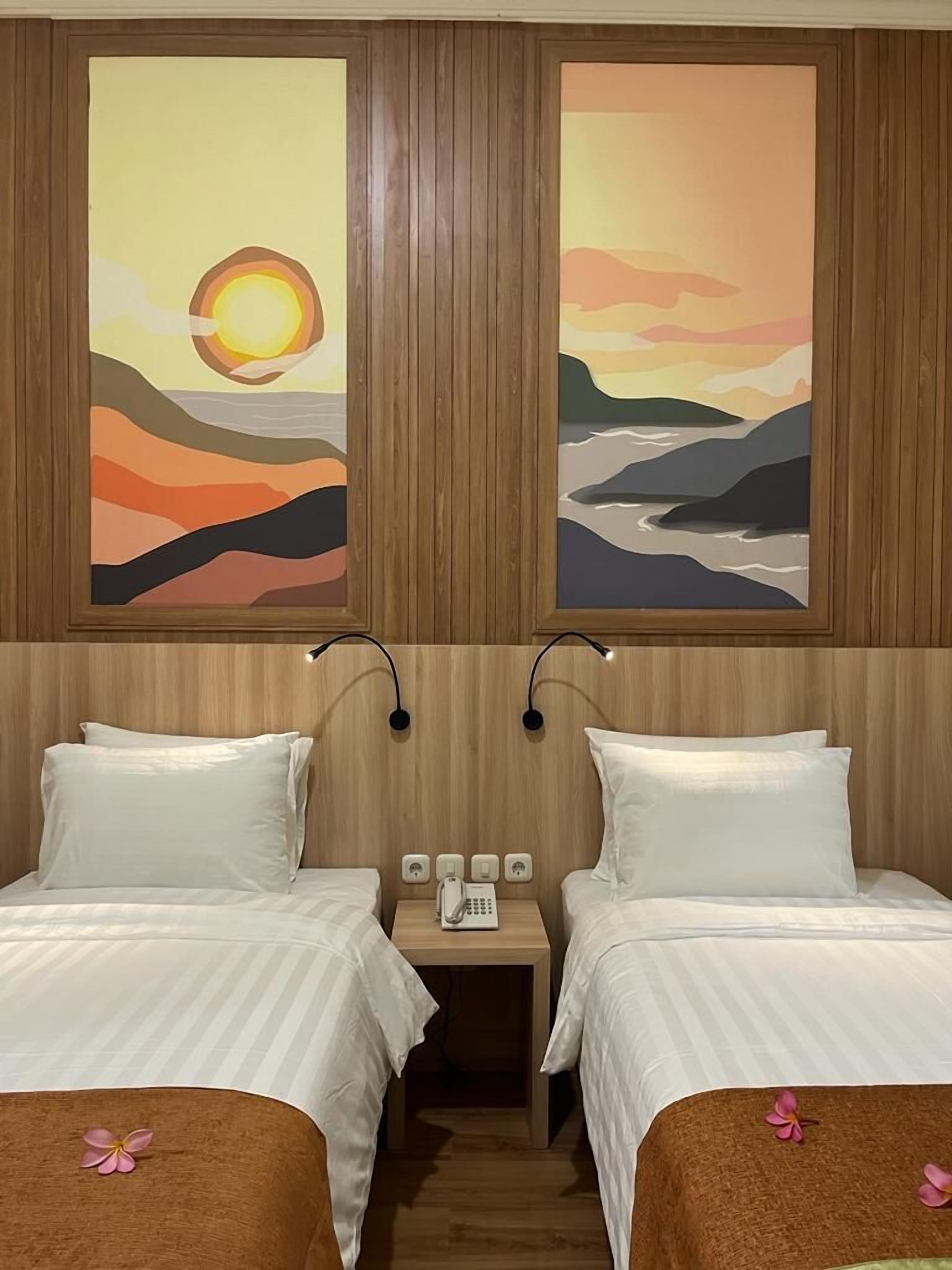 Habitación de hotel con dos camas, cabecero de madera y dos cuadros de paisajes.