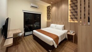 Una habitación de hotel moderna con una cama grande, un escritorio, una silla y un televisor.