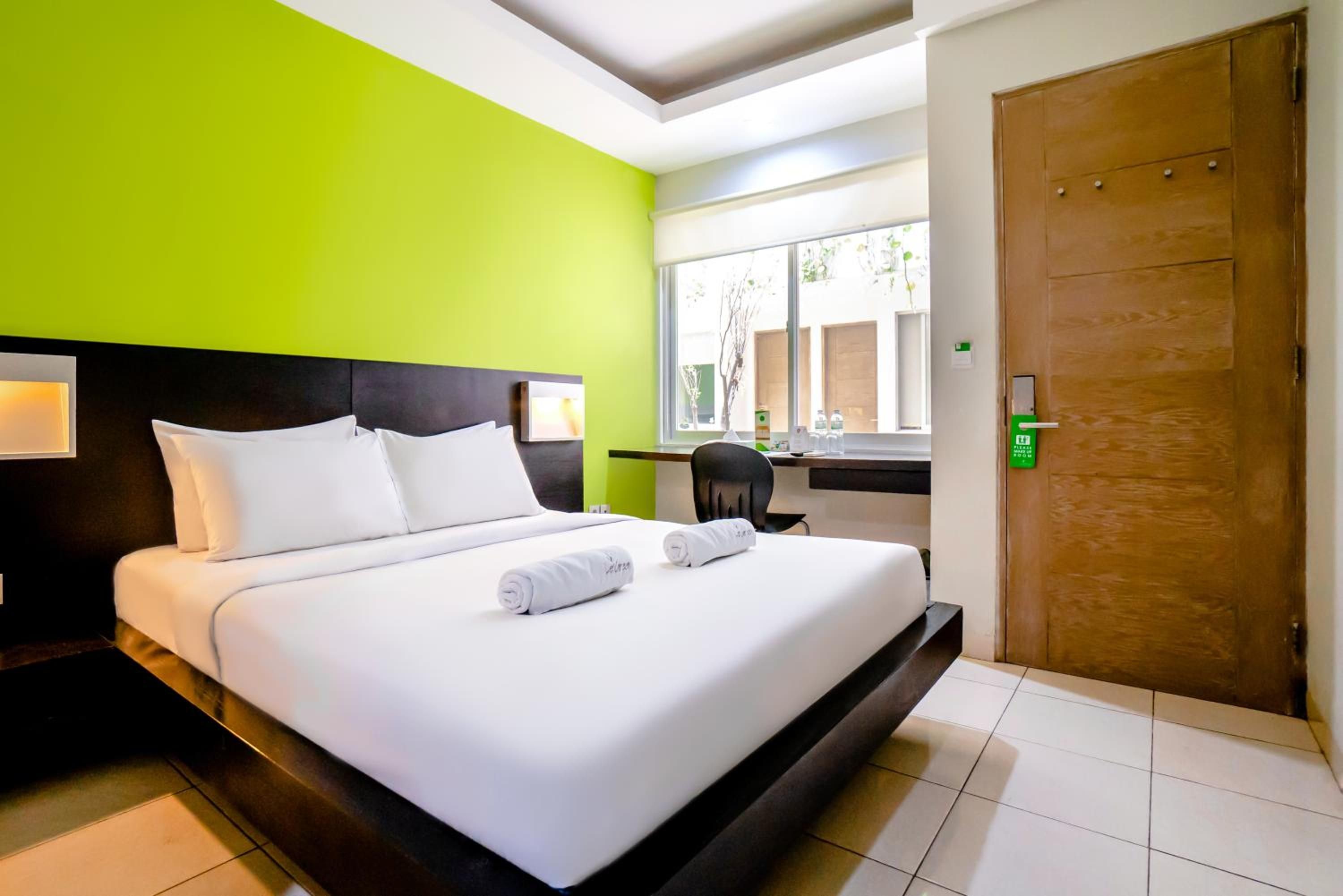 Una habitación de hotel con cama, escritorio, silla, ventana y puerta.