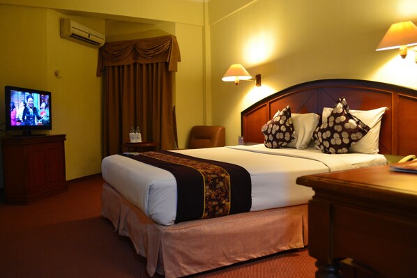 A hotel room with a bed, a television, a desk, and a chair. - Mega Matra Hotel (Jakarta)