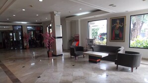 Um hall de entrada com piso de mármore, um sofá, uma mesa de centro e um vaso de planta.