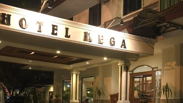 Entrada de um hotel com uma placa que diz 'HOTEL MEGA'.