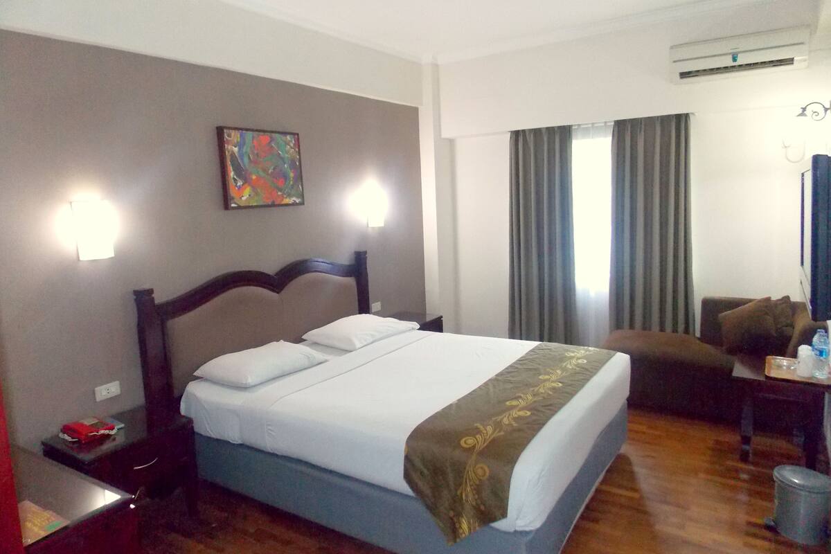 Ein Hotelzimmer mit Bett, Schreibtisch, Stuhl und einem Bild an der Wand.