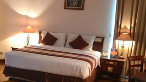 A hotel room with a large bed, two bedside lamps, a nightstand, and a chair. - Hotel Sentral Jakarta (Jakarta)